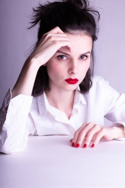 Dudaklarında kırmızı ruj lekesi olan beyaz arka planda beyaz gömlekli güzel bir genç kız.