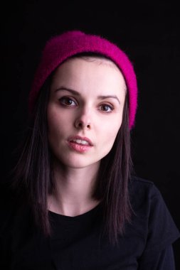 Pembe şapkalı güzel bir genç kız. Stüdyo siyah arka plan.