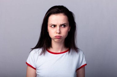 Gri arka planda kırmızı beyaz tişörtlü çekici duygusal kız.