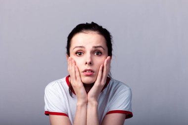 Gri arka planda kırmızı beyaz tişörtlü çekici duygusal kız.