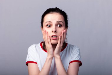 Gri arka planda kırmızı beyaz tişörtlü çekici duygusal kız.