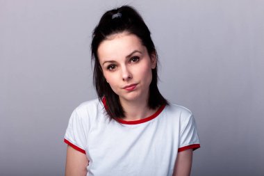 Gri arka planda kırmızı beyaz tişörtlü çekici duygusal kız.