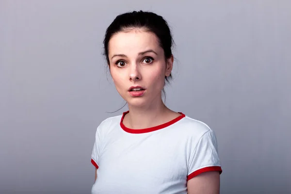 Vonzó Érzelmi Lány Piros Fehér Pólóban Szürke Háttérrel — Stock Fotó