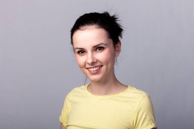 Gri arka planda sarı tişörtlü genç duygusal kız.