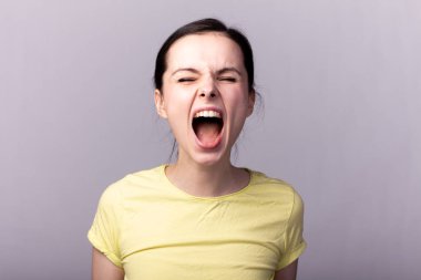 Gri arka planda sarı tişörtlü genç duygusal kız.