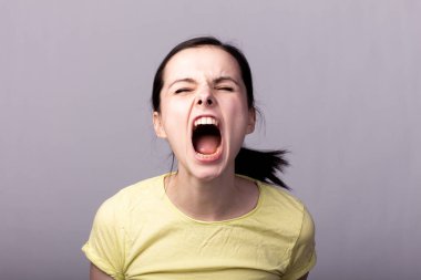 Gri arka planda sarı tişörtlü genç duygusal kız.