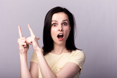 Gri arka planda sarı tişörtlü genç duygusal kız.