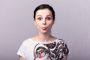 Gri arka planda tişörtlü genç duygusal kız.