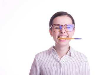 Güzel duygusal kız gömlekli ve gözlüklü beyaz arka planda bir kalemi ağzıyla tutuyor.