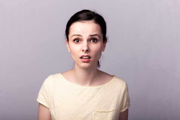 young emotional girl in a yellow t-shirt on a gray background