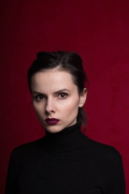 Dudaklarında kırmızı ruj lekesi olan siyah balıkçı yakalı bir kız.