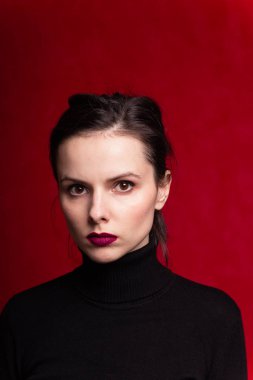 Dudaklarında kırmızı ruj lekesi olan siyah balıkçı yakalı bir kız.