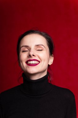 Dudaklarında kırmızı ruj lekesi olan siyah balıkçı yakalı bir kız.