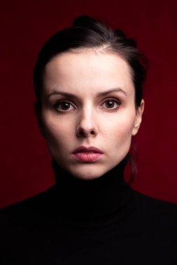 Kırmızı arka planda siyah balıkçı yakalı duygusal kız.