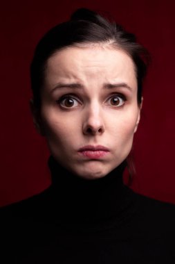 Kırmızı arka planda siyah balıkçı yakalı duygusal kız.