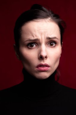 Kırmızı arka planda siyah balıkçı yakalı duygusal kız.