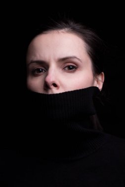 Siyah arka planda siyah balıkçı yakalı duygusal bir kız.