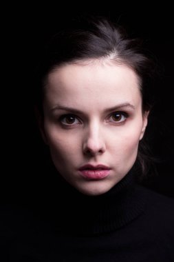 Siyah arka planda siyah balıkçı yakalı duygusal bir kız.