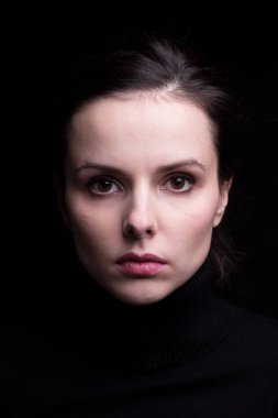 Siyah arka planda siyah balıkçı yakalı duygusal bir kız.