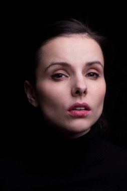 Siyah arka planda siyah balıkçı yakalı duygusal bir kız.