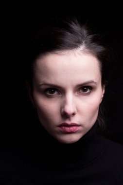 Siyah arka planda siyah balıkçı yakalı duygusal bir kız.