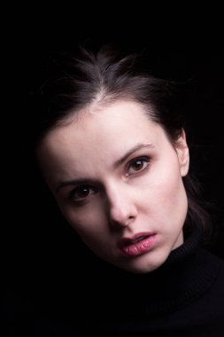 Siyah arka planda siyah balıkçı yakalı duygusal bir kız.