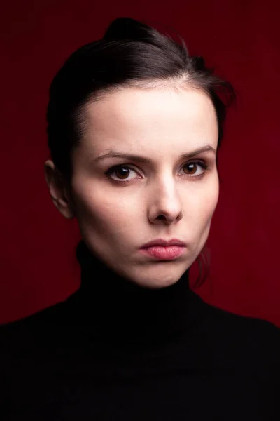 emotional girl in a black turtleneck on a red background