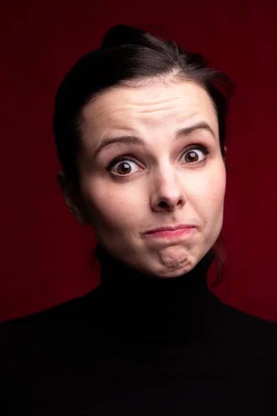 emotional girl in a black turtleneck on a red background