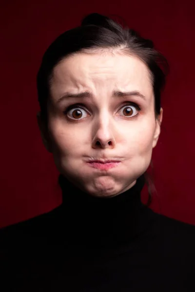 emotional girl in a black turtleneck on a red background