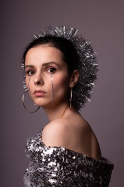 Güzel bir elbise içinde güzel bir kız. Yüzünde yapay elmaslar olan parlak bir daire.