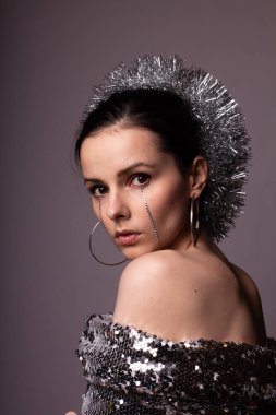 Güzel bir elbise içinde güzel bir kız. Yüzünde yapay elmaslar olan parlak bir daire.