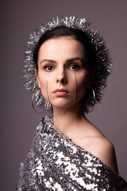 Güzel bir elbise içinde güzel bir kız. Yüzünde yapay elmaslar olan parlak bir daire.