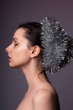 Çıplak omuzlu bir kızın profil portresi, gösterişli saçlar, yapay elmasların yüzünde.