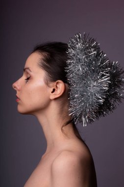 Çıplak omuzlu bir kızın profil portresi, gösterişli saçlar, yapay elmasların yüzünde.