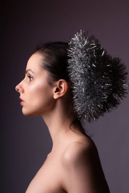 Çıplak omuzlu bir kızın profil portresi, gösterişli saçlar, yapay elmasların yüzünde.