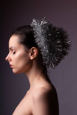 Çıplak omuzlu bir kızın profil portresi, gösterişli saçlar, yapay elmasların yüzünde.