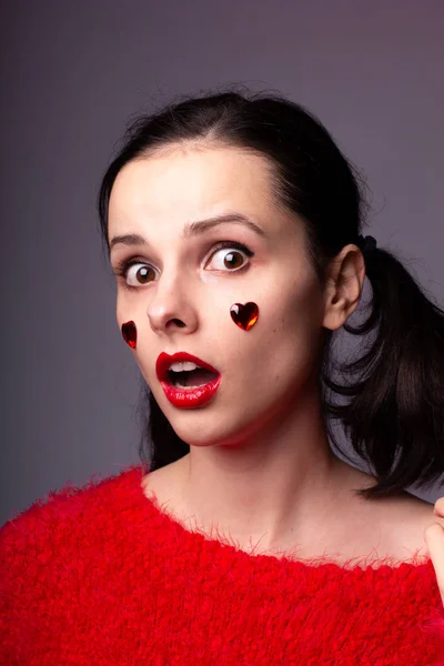 girl in a red sweater with red lips and a red heart on her face