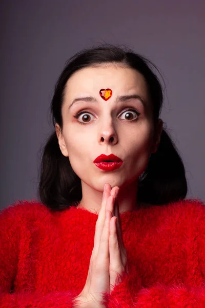 girl in a red sweater with red lips and a red heart on her face