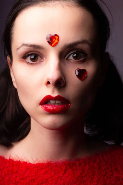 girl in a red sweater with red lips and a red heart on her face