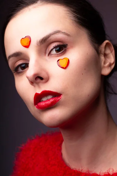 girl in a red sweater with red lips and a red heart on her face