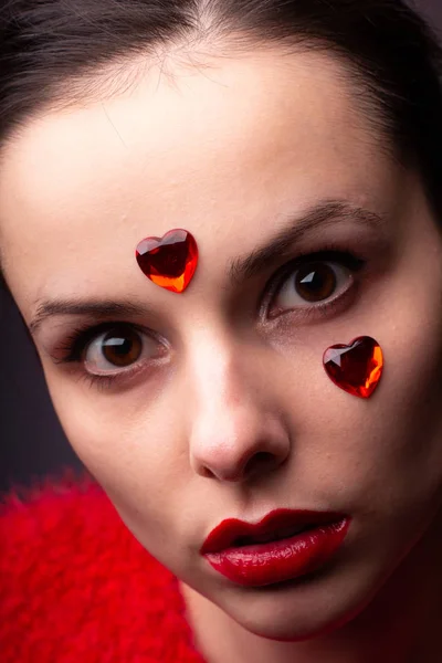 girl in a red sweater with red lips and a red heart on her face