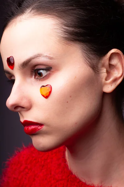 girl in a red sweater with red lips and a red heart on her face