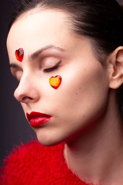 girl in a red sweater with red lips and a red heart on her face