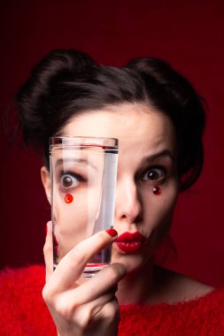 Kırmızılı duygusal kız elinde bir bardak su tutuyor.