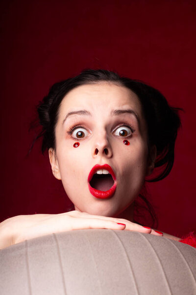 эмоциональная девушка в красном держит стакан воды в руках
