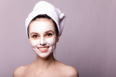 Kafasında beyaz havluyla yüzünde maske olan bir kız.