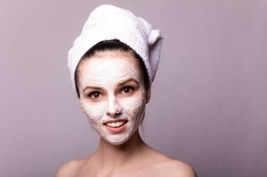 Kafasında beyaz havluyla yüzünde maske olan bir kız.