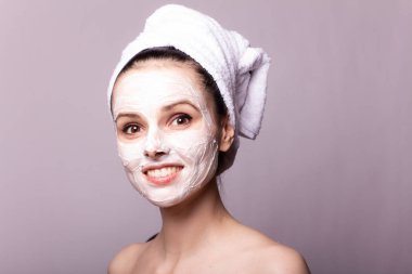 Kafasında beyaz havluyla yüzünde maske olan bir kız.