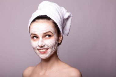 Kafasında beyaz havluyla yüzünde maske olan bir kız.