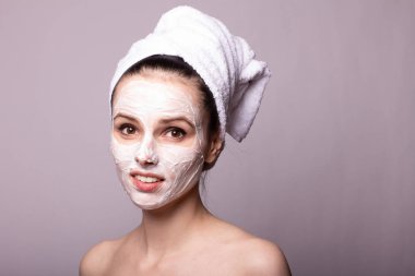 Kafasında beyaz havluyla yüzünde maske olan bir kız.